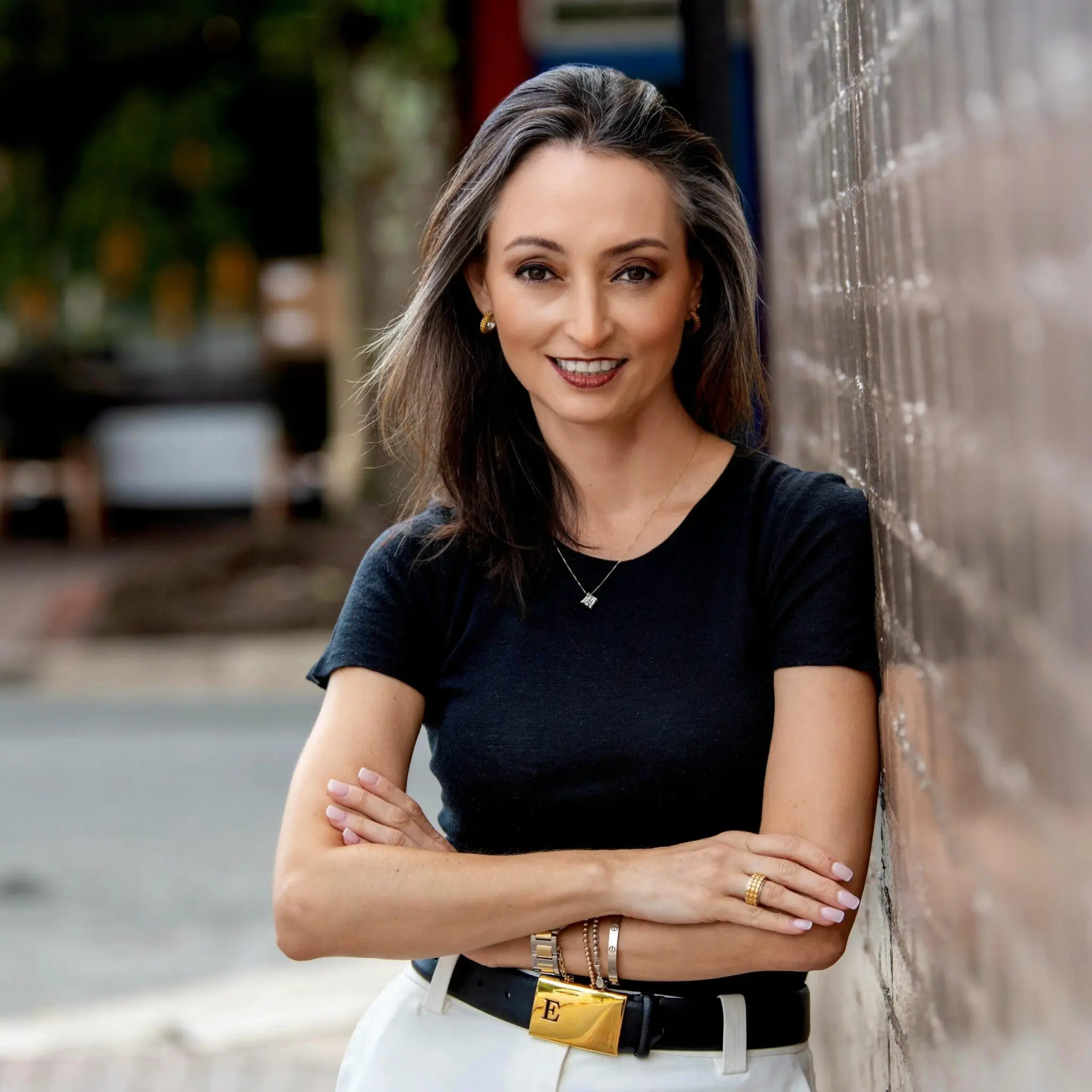 One Global founding partner with long brown hair smiling outside near a brick wall.