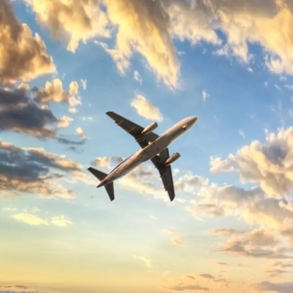 Aeroplane flying in partly cloudy sunset sky, Europe business air travel concept.