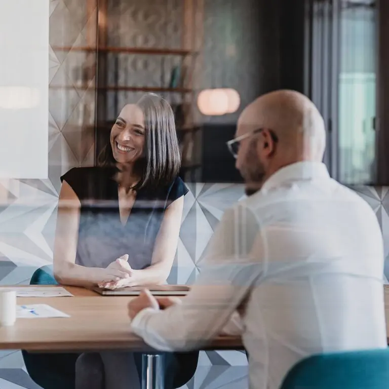 Two people meet at a table with local experts discussing travel solutions.