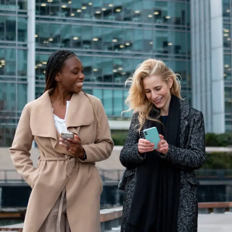 Two women use mobiles to check travel solutions in the city.