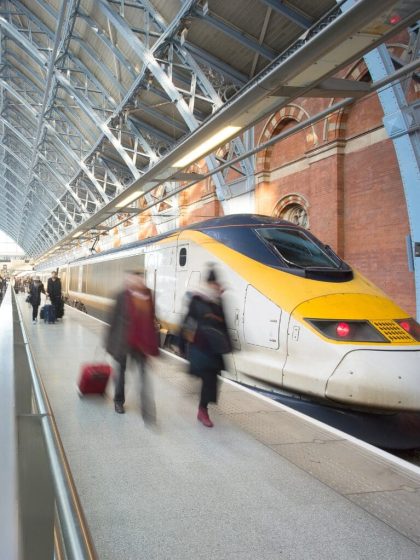 High-speed train at busy station, business travel management, glass roof.