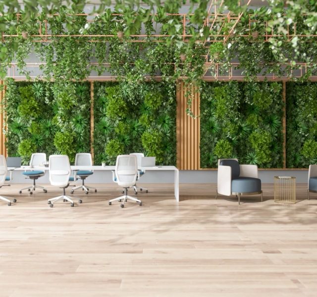 Modern office space with desks, chairs, plant walls, and natural light for business travellers.