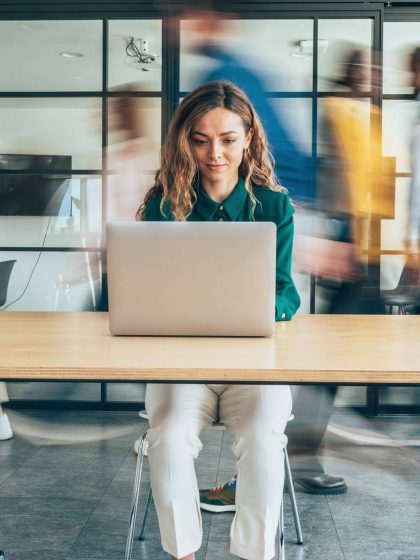 Woman on laptop at desk working on Business Travel Management in office.