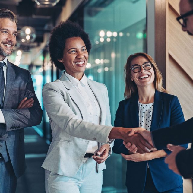 Business professionals at One Global Way, two shaking hands in an office corridor.