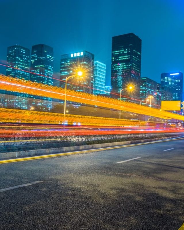 Night cityscape with light trails and lit buildings on One Global Way.