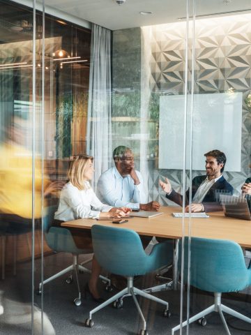 People meeting in a modern office with a travel expert walking by in motion blur.